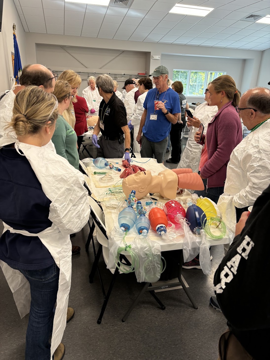 Workshop participants gather around a table for a hands-on airway and cardiopulmonary demonstration.